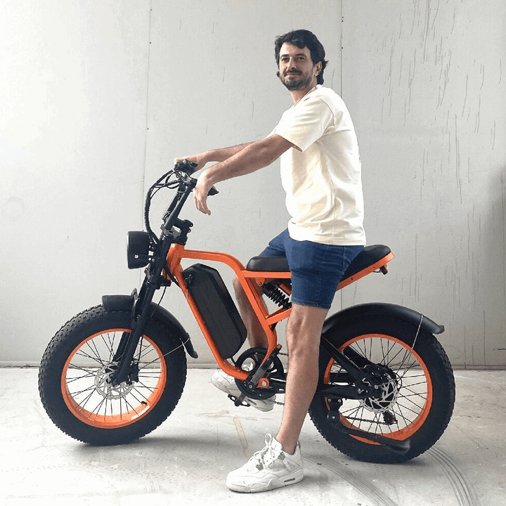 Person riding orange Boombike Bluvall SU8 moped ebike with 52V 1500W motor and 60-mile range.